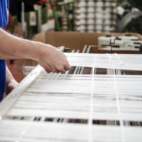 Zwei Mitarbeiter begutachten die einzelnen Fäden des Stoffes auf der Webmaschine