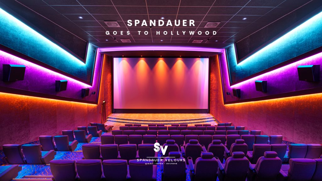 „Werbegrafik mit dem Titel ‚SPANDAUER GOES TO HOLLYWOOD‘. Das Bild zeigt den Innenraum eines modernen Kinosaals mit violetten Sesseln und farbiger Neon-Beleuchtung. Unten das Logo von SPANDAUER VELOURS.“