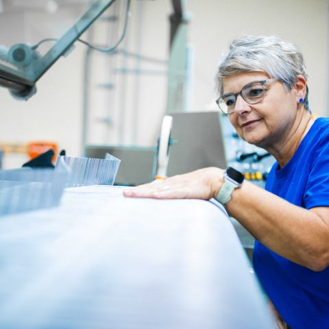Mitarbeiterin bei der manuellen Qualitätsprüfung der Gewebeoberfläche an einer industriellen Spinnmaschine bei Spandauer Velours.