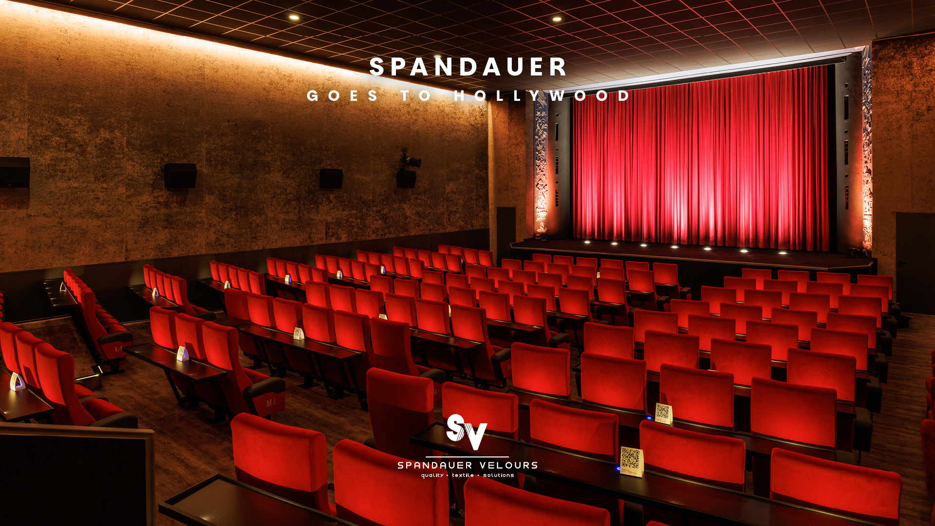 Moderner Kinosaal mit roten Samtsesseln, der Wandbespannung Virginia, und Vorhang Viola von Spandauer Velours – Referenzprojekt.Der Spruch „Spandauer goes to Hollywood“ steht auf dem Bild.