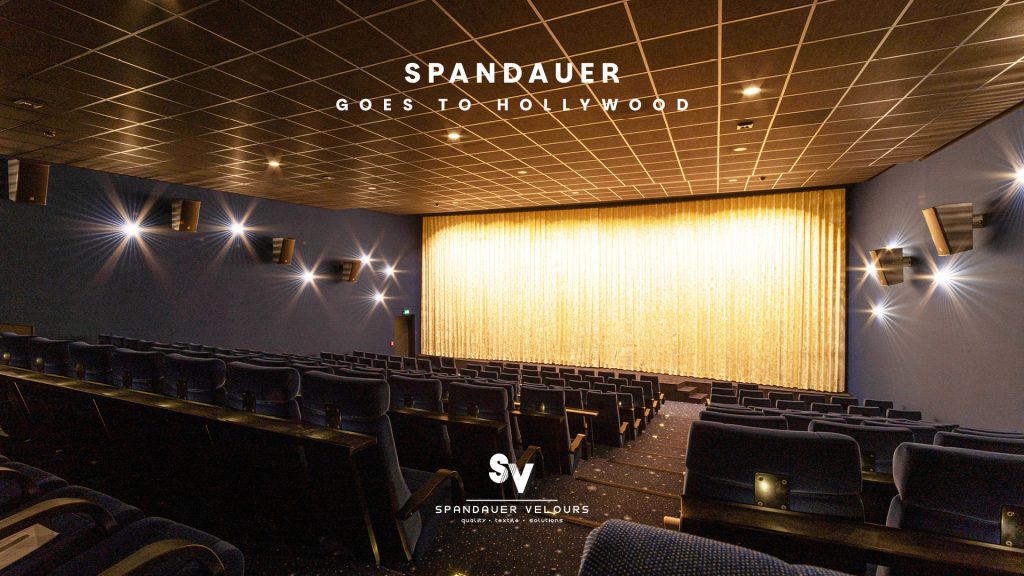 Moderner Kinosaal mit blauen Samtsitzen und goldenem Bühnenvorhang von Spandauer Velours unter dem Motto Spandauer goes to Hollywood.