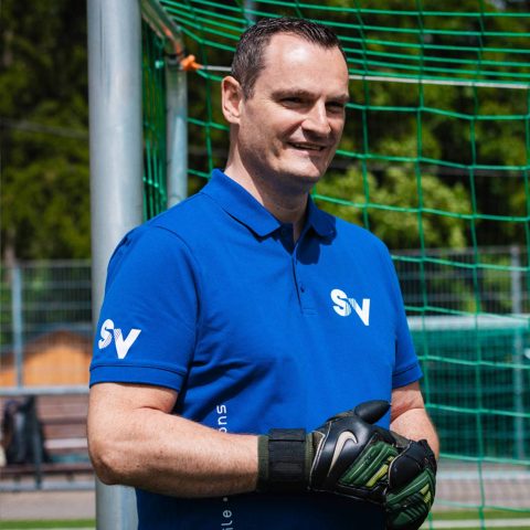 10. Porträt von Herrn Martin im blauen Spandauer Velours Poloshirt mit Torwarthandschuhen vor dem Fußballtor beim Erzieher-Elfmeterschießen.