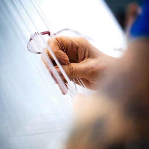 Handarbeit in der Textilherstellung: Eine Mitarbeiterin sortiert präzise feine Garnfäden an der Webe-Maschine bei Spandauer Velours.
