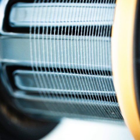 Nahaufnahme der Garnführung mit parallel gespannten, feinen Fäden auf einer Spule in der Weberei von Spandauer Velours.