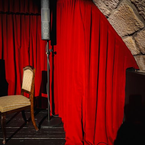 Maßanfertigung eines roten Theater-Bühnenvorhangs von Spandauer Velours, der passgenau an die Rundung einer bogenförmigen Naturstein-Gewölbedecke im Kügelgenhaus Dresden angepasst ist.